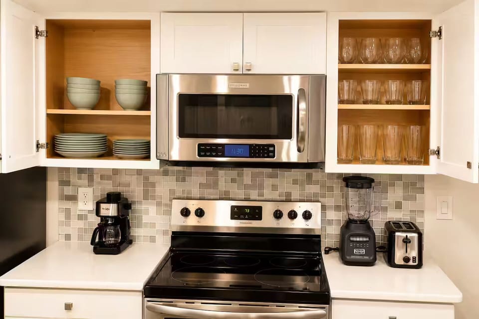 Well-stocked kitchen with cookware, dishes, and glassware.
