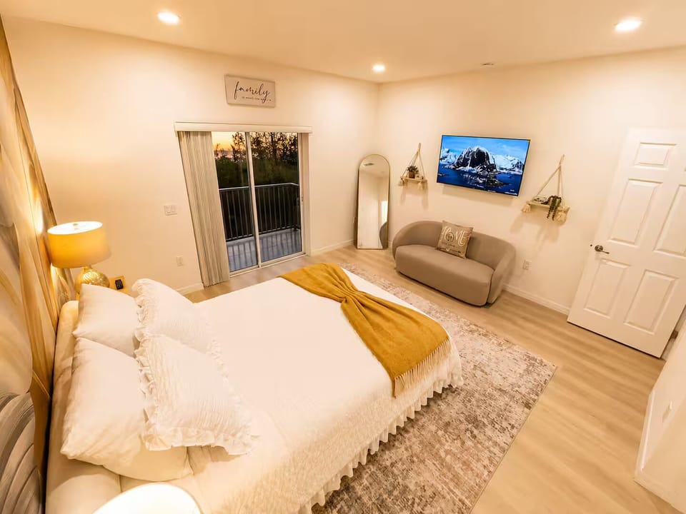 Spacious bedroom with a queen bed, sitting area, Smart TV, and private balcony.