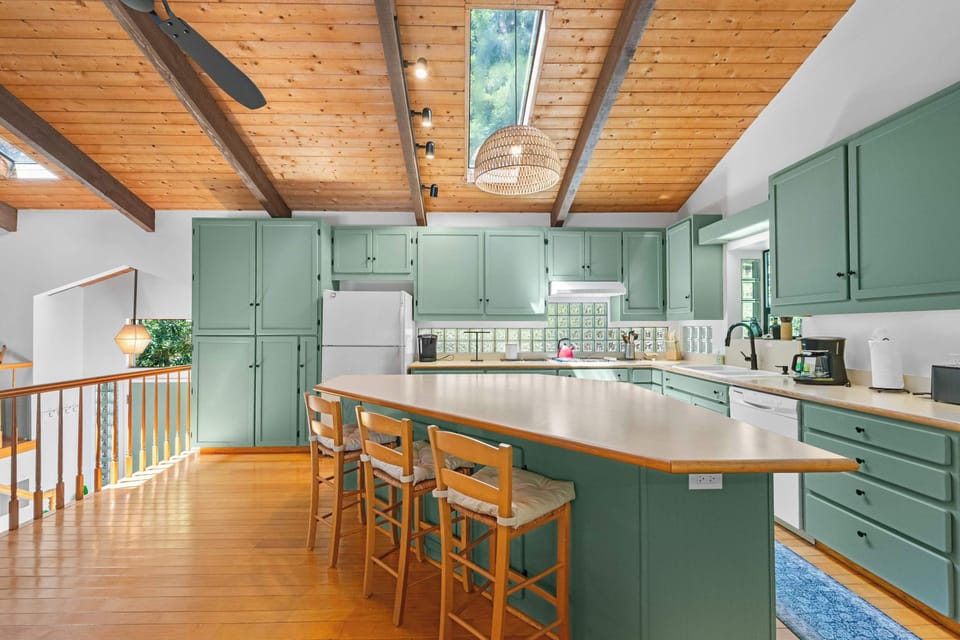 Glass-block backsplash and a gooseneck faucet over the sink—prep with the trees visible through the window above.