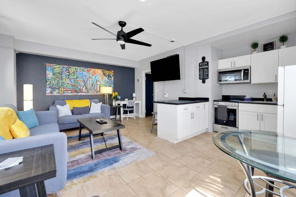 Open-concept heart of the condo. Living room, a full kitchen setup, and a dedicated work area that adds tremendous value for remote workers and travelers alike.