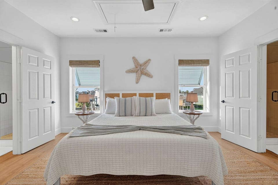Coastal king bedroom with matching nightstands, starfish wall decor, and soft neutral bedding.