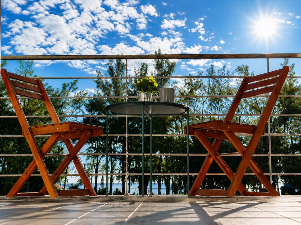 Sunny balcony with cozy seating and peaceful treetop and ocean views