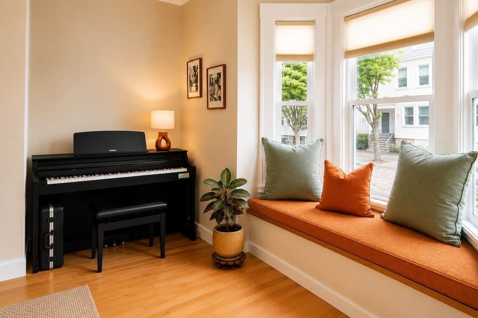 The living room features new furniture, a smart TV with soundbar, a comfortable recliner, bookshelves with many books, board games, exercise weights, and a piano. A cozy, stylish space perfect for relaxing, reading, music, and spending time together.