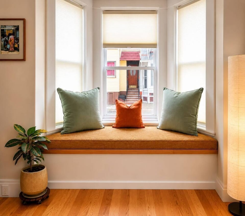 The living room features new furniture, a smart TV with soundbar, a comfortable recliner, bookshelves with many books, board games, exercise weights, and a piano. A cozy, stylish space perfect for relaxing, reading, music, and spending time together.