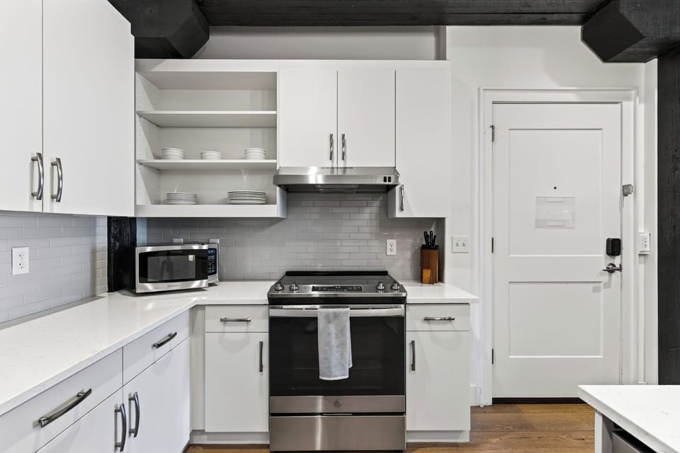 Clean, fully equipped modern kitchen with stainless steel appliances, gas range, and white cabinetry.