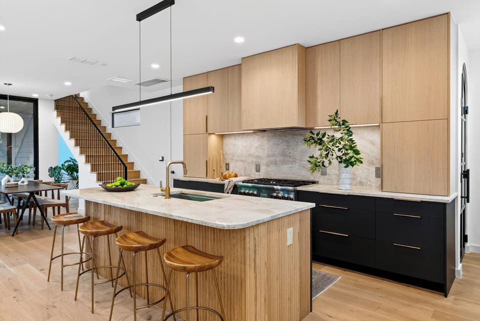 Warm modern kitchen with a fluted island, sleek black accents, and bar seating beside the dining area.
