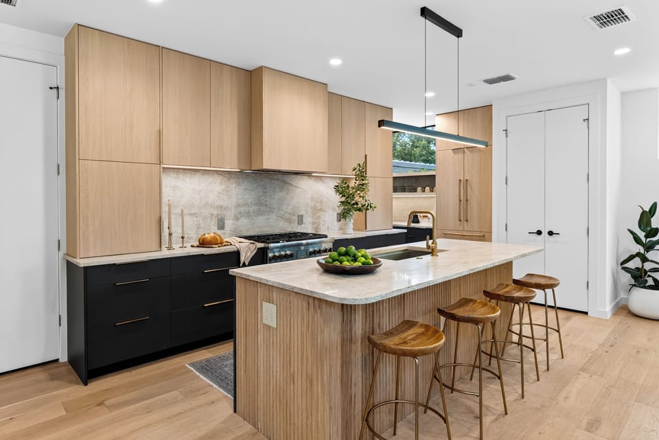 Warm modern kitchen with a fluted island, sleek black accents, and bar seating beside the dining area.