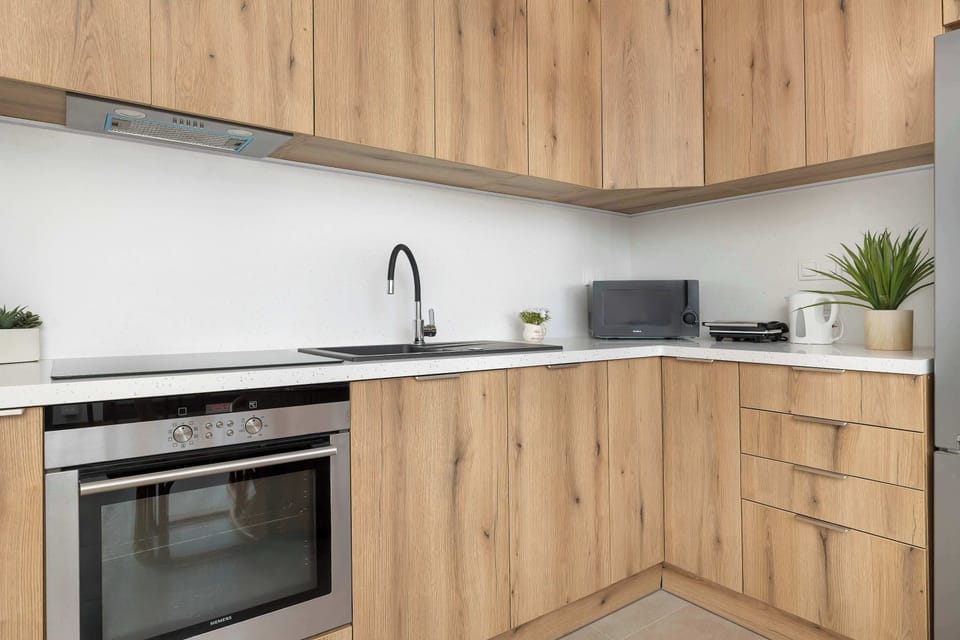 A equipped kitchenette with an oven, stovetop, and sink. Wooden finishes give it a warm look.