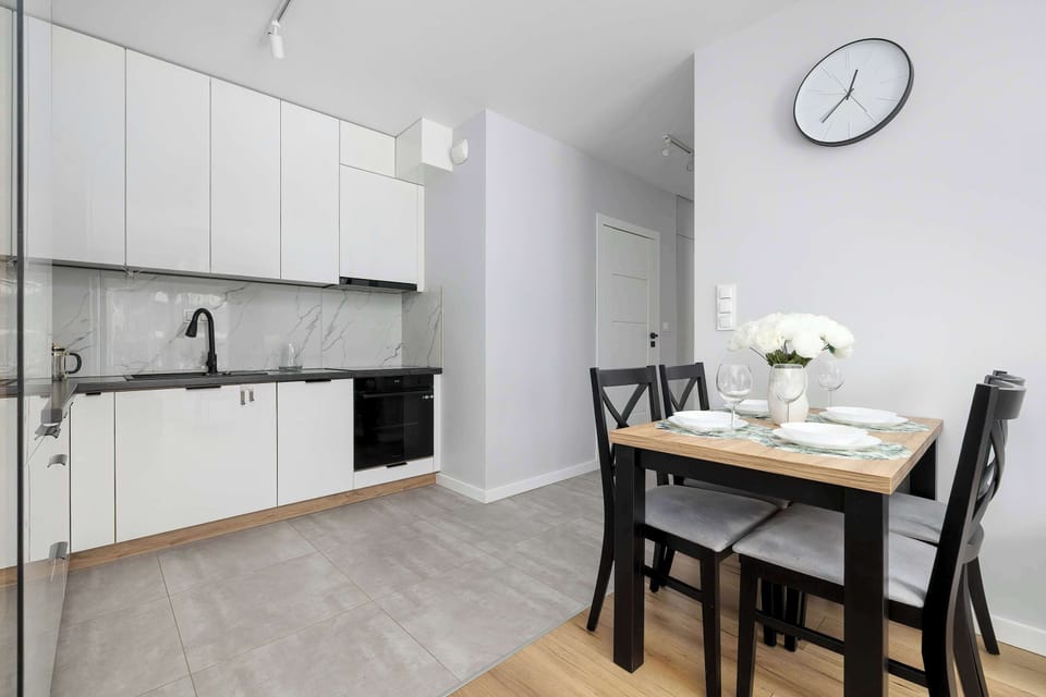 The kitchenette area transitions directly into the dining space, where a wooden table and black chairs are neatly positioned. 