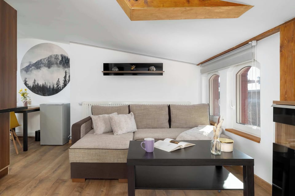 A modern living room includes a sectional couch, a coffee table, and an adjacent dining area in an open layout. Warm wood accents enhance the inviting atmosphere.