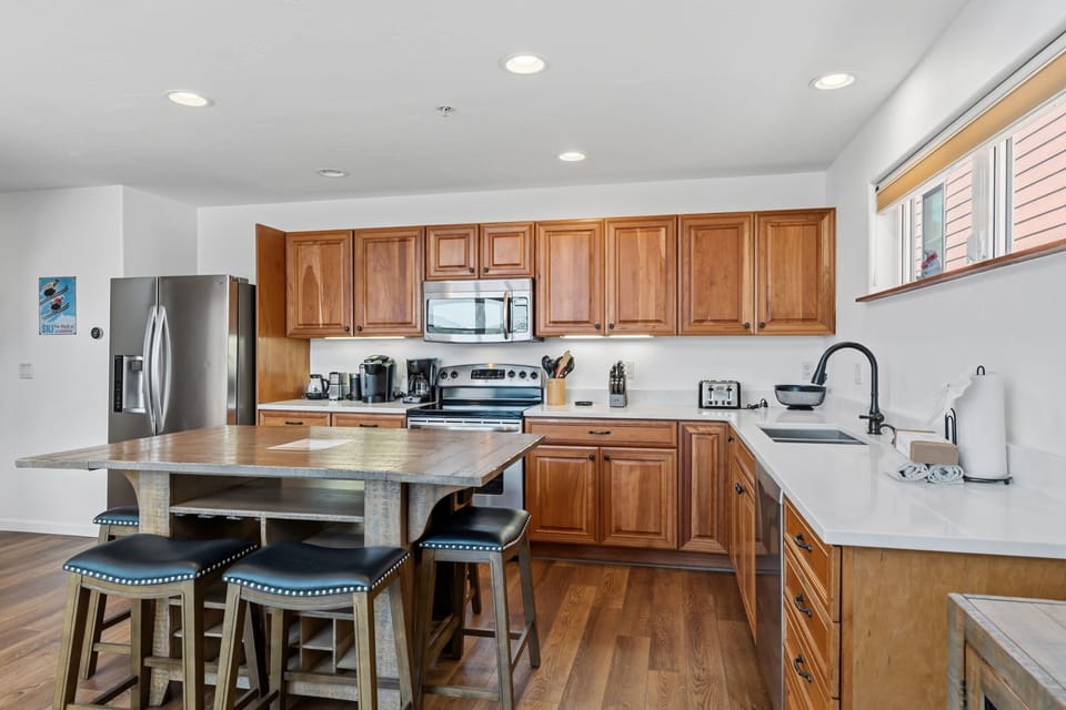 Your fully equipped kitchen awaits with stainless steel appliances, ample counter space, and a central island perfect for preparing meals or enjoying morning coffee together.