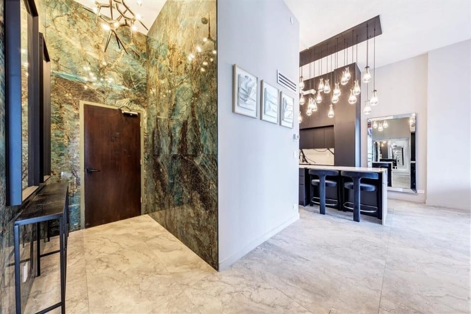 Show-stopping entryway featuring a dramatic green marble accent wall and ceiling with twinkling lights. This artful welcome flows into the open kitchen with its glamorous pendant lighting, setting the tone for a truly unique stay.