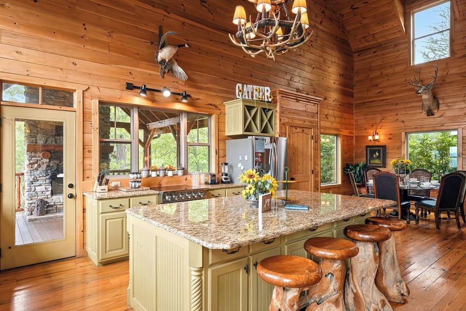 Your rustic mountain retreat features a stunning kitchen where you'll love gathering around the granite island with handcrafted log stools, surrounded by warm wood walls and natural light streaming through every window.