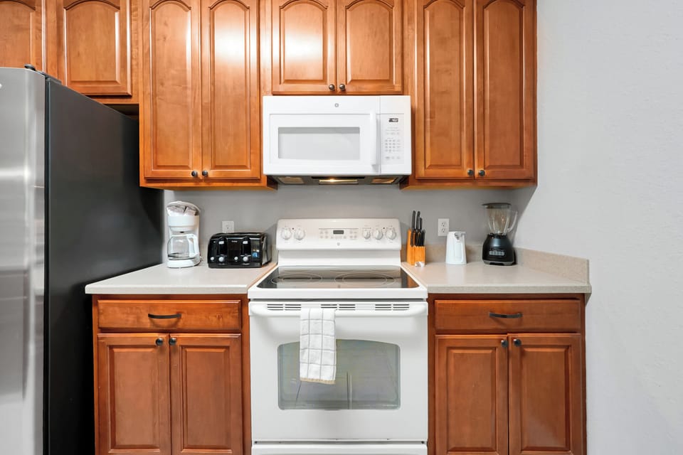 Your fully equipped kitchen features warm wood cabinetry, stainless steel appliances, and everything you need to prepare meals during your stay—including a coffee maker, toaster, and blender for easy mornings.