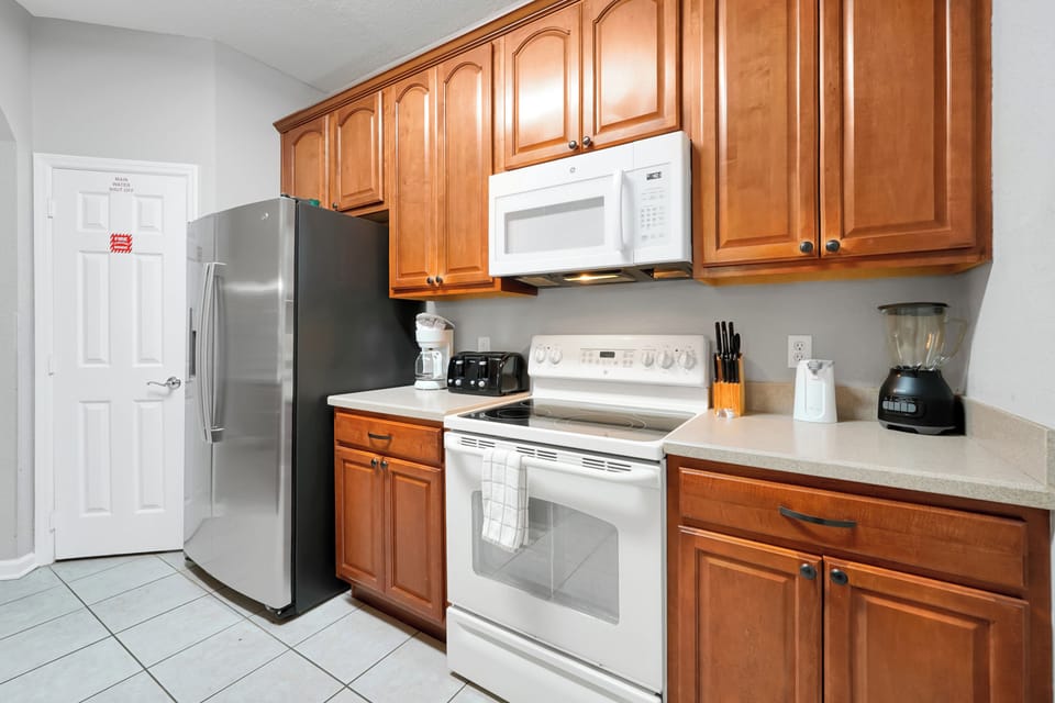 Step into a welcoming kitchen where warm wood cabinetry and modern stainless appliances are ready for your culinary adventures, with a spacious layout offering everything you need to prepare meals during your stay.