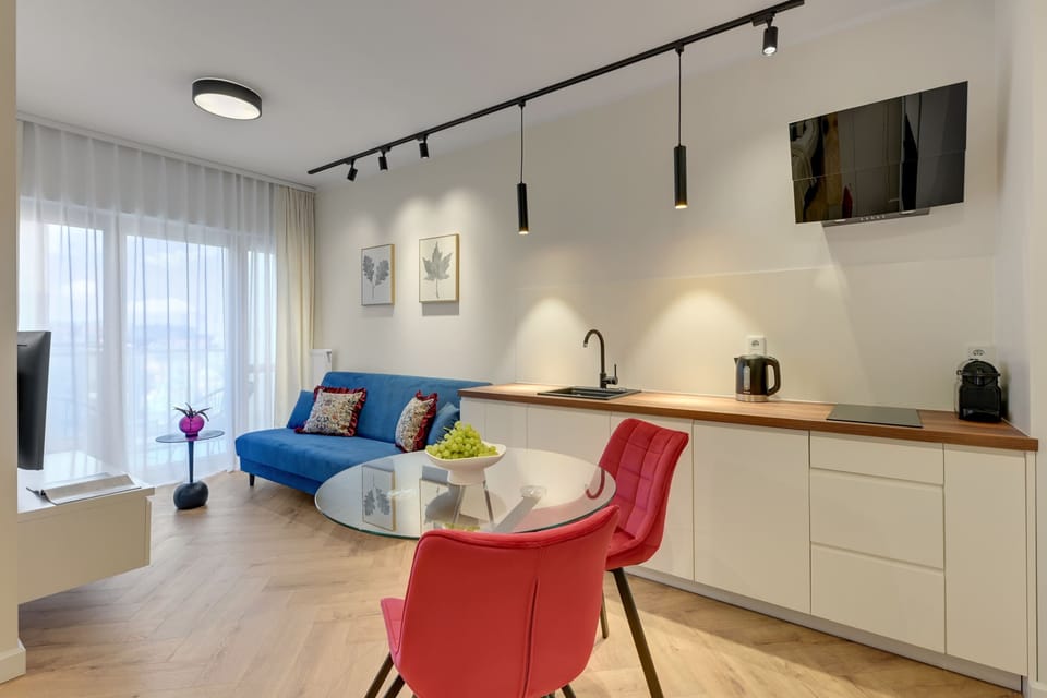 Przestrzeń dzienna została zaprojektowana z myślą o komforcie i odpoczynku. Znajduje się tu wygodna rozkładana sofa. Naprzeciwko ustawiono telewizor z funkcją Smart TV, idealny do wieczornego relaksu przy ulubionym filmie lub serialu.