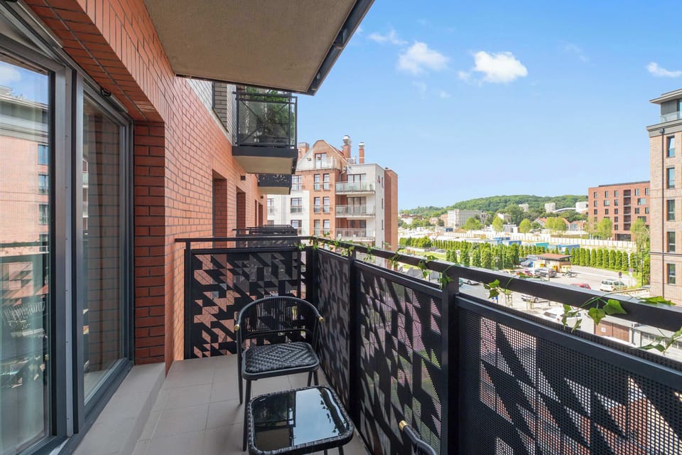 Z apartamentu można wyjść na umeblowany balkon wyposażony w stolik i dwa krzesła. Balkon wychodzi na wewnętrzny dziedziniec i zabudowę inwestycji, tworząc przyjemne miejsce na poranną kawę lub odpoczynek na świeżym powietrzu.