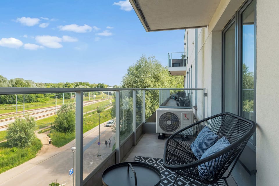 Duże przeszklenia zapewniają dostęp do naturalnego światła i prowadzą na przestronny balkon wyposażony w meble wypoczynkowe. Dzięki położeniu na wyższym piętrze goście mogą cieszyć się otwartym widokiem na okolicę.