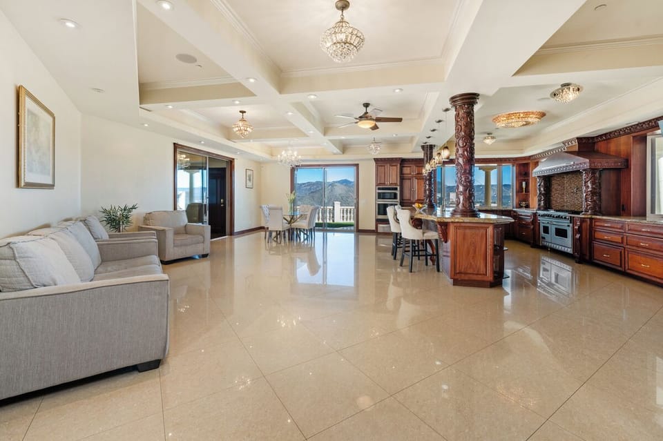 The great room holds it all, sofas at one end and hillside windows at the other.