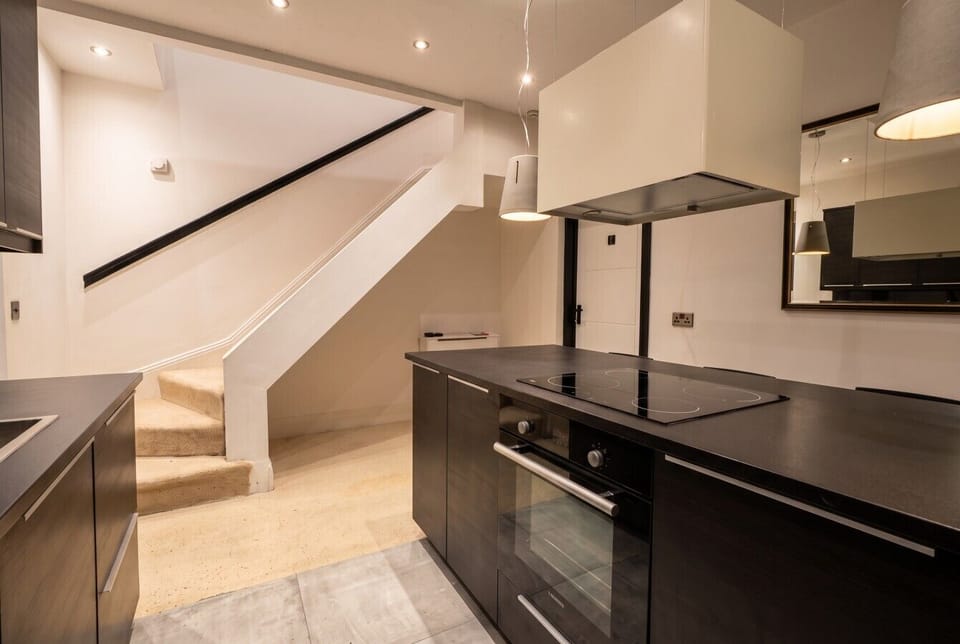 Full kitchen with oven, hob and stairs to more space