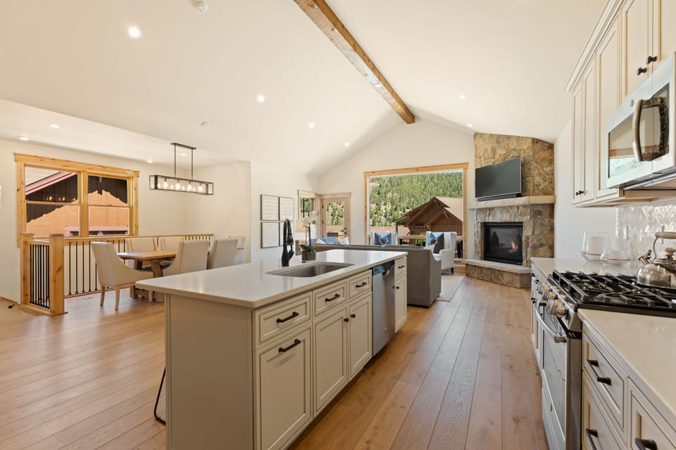 Imagine preparing meals in this spacious kitchen with its island workspace, designer appliances, and cozy stone fireplace—your perfect mountain retreat for cooking and gathering with loved ones.