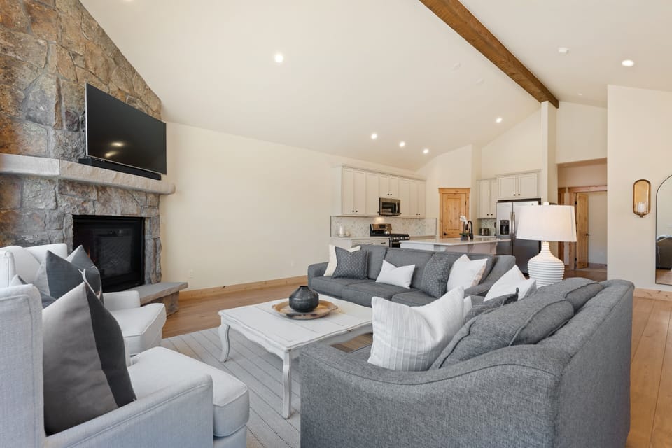 Gather with loved ones in this bright, open-concept space where soaring vaulted ceilings and a cozy stone fireplace create the perfect retreat for memorable evenings together.