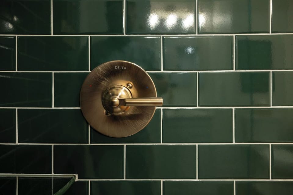 Elegant shower with deep green tile and brushed brass fixtures