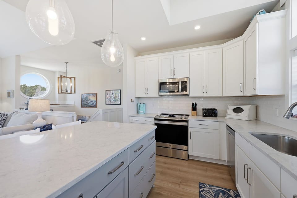 Fully Equipped Kitchen w/ a spacious island counter withe seating, flowing into the open-concept living area.
