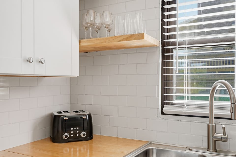 Bright modern kitchen with subway tile, open shelving, and natural light