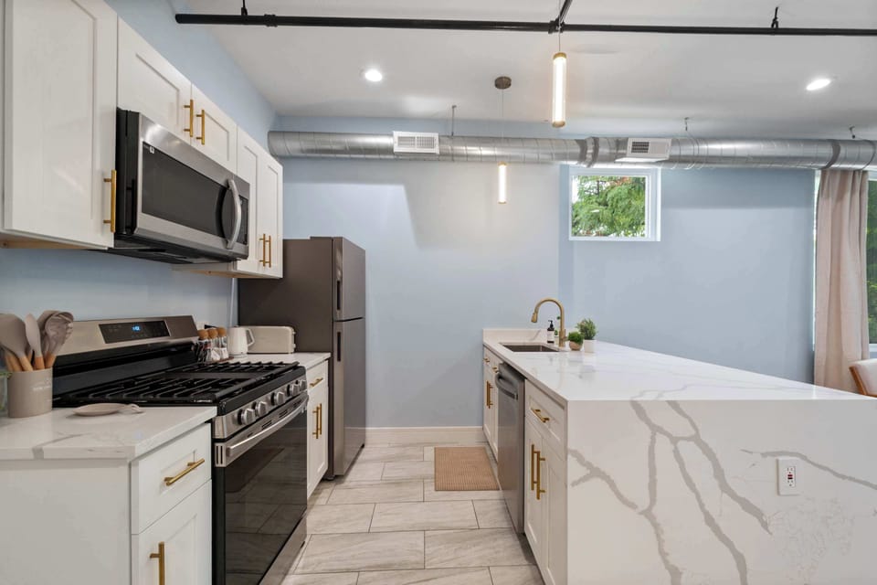 Modern kitchen w/ sleek counters & pendant lighting overhead.