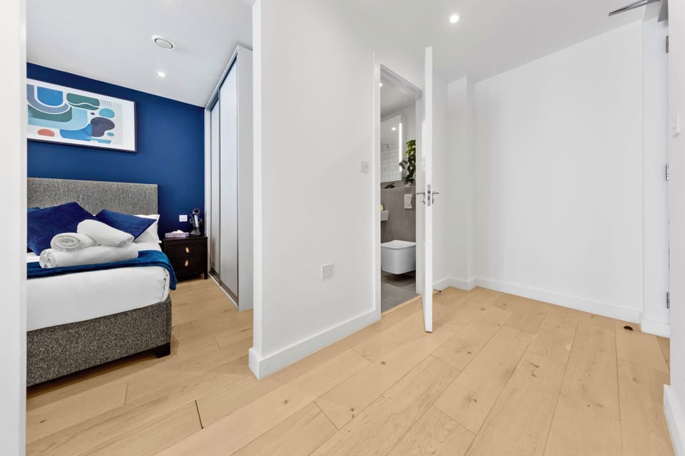 Stylish bedroom with en-suite access, mirrored wardrobe, and bold blue accents