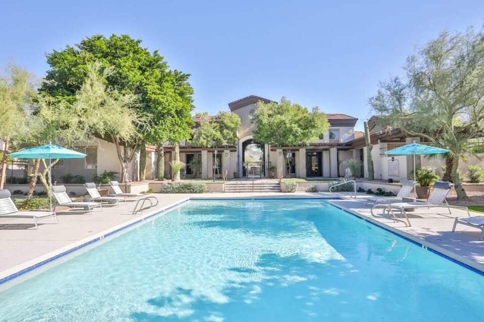 Resort-style pool with loungers, umbrellas, and sunny courtyard vibes