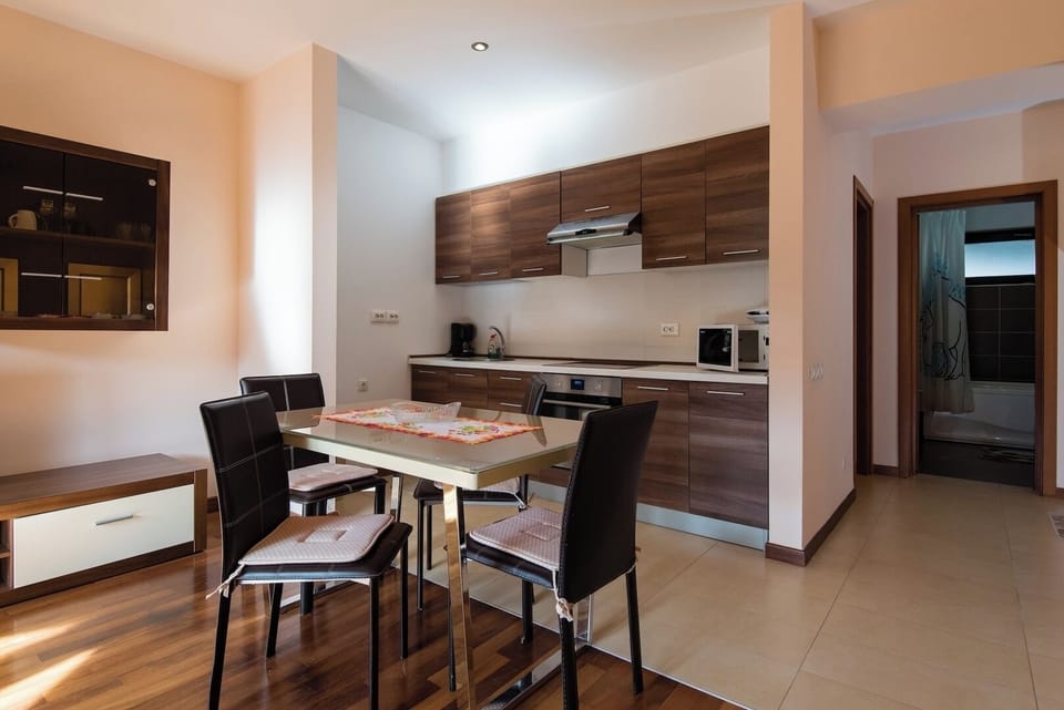 Fully equipped mountain kitchen with walnut cabinetry, extractor hood, microwave, electric kettle and dining table for 4. Well-set-up for self-catering stays in Sia Apartment, Predeal resort centre.