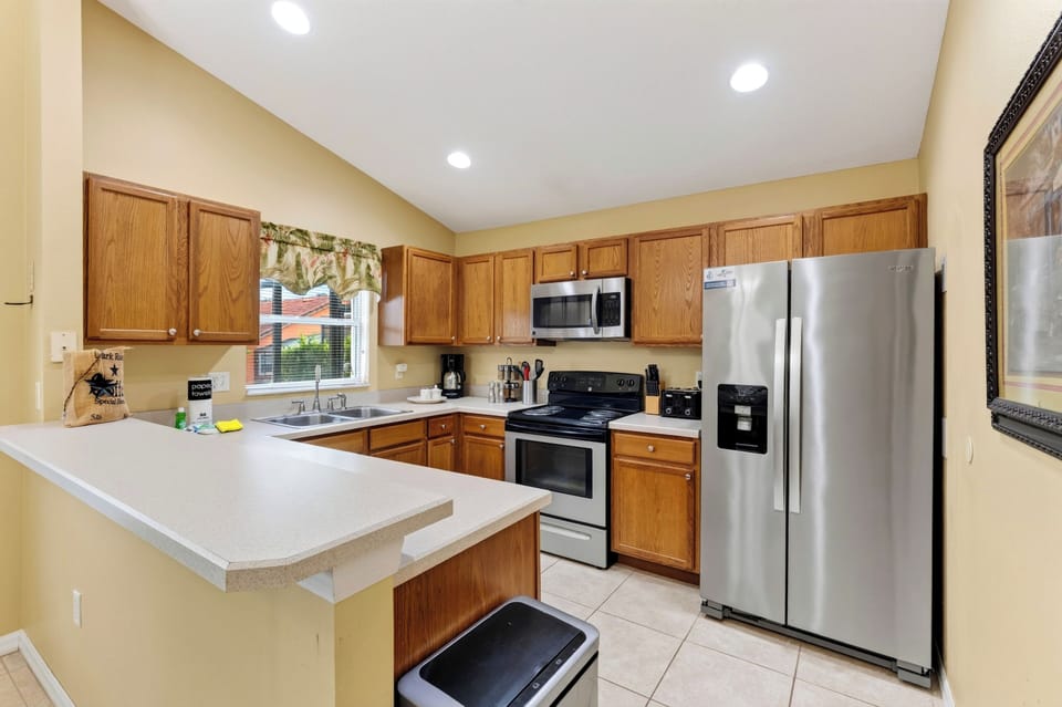 Bright, functional kitchen featuring a raised breakfast bar and spacious stainless steel refrigerator.