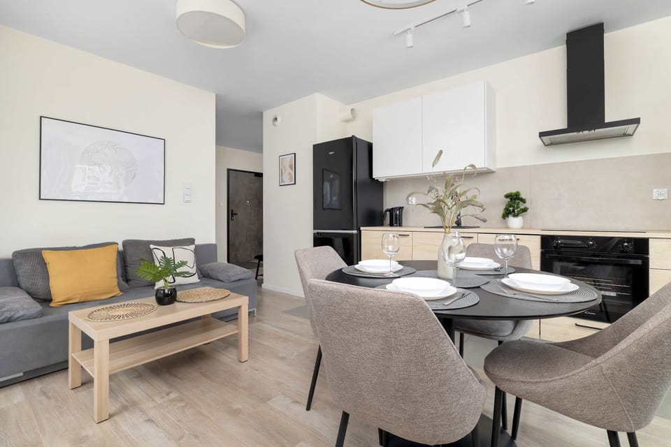 An open layout combining a kitchen, dining room, and living area. A round dining table with upholstered chairs sits near the kitchen setup.
