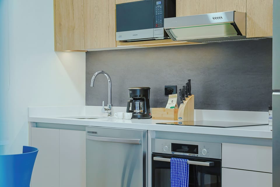 Your fully equipped kitchen features a stove, microwave, coffee maker, and sleek modern countertops—perfect for preparing meals and starting your mornings right.