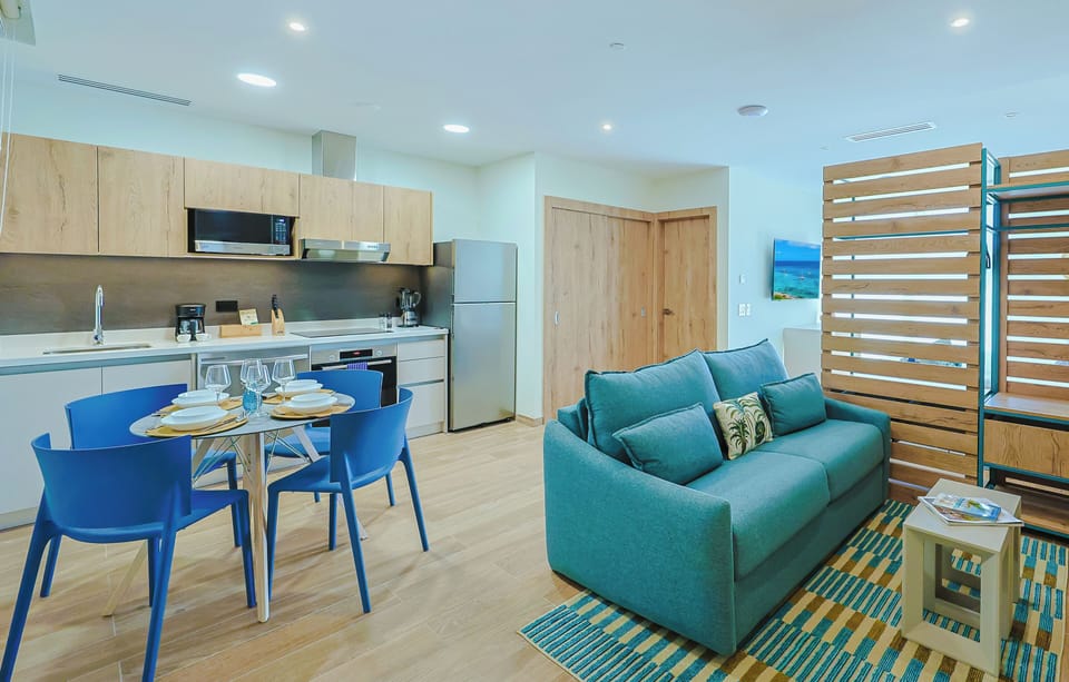Your bright, modern living space invites relaxation with a plush turquoise sofa, fully equipped kitchen, and cheerful dining area—perfect for cozy meals and unwinding after exploring the area.