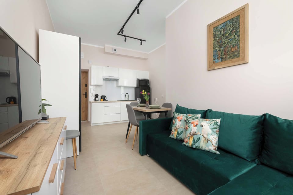 A view of the living room with a green sofa and open-plan design. The apartment has a bright and modern interior.