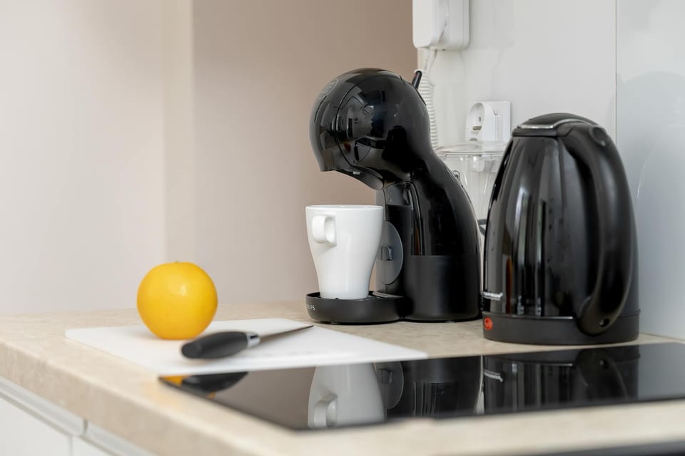 A coffee machine and an electric kettle are placed on the kitchen counter. The kitchenette is equipped for preparing hot drinks.