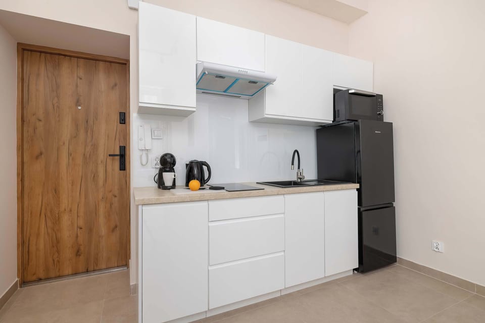 A modern kitchenette with white cabinets and built-in appliances. The open layout feels bright and functional.