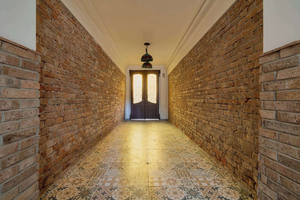 A brick-lined hallway leading to the building entrance. Decorative lighting creates a welcoming atmosphere.
