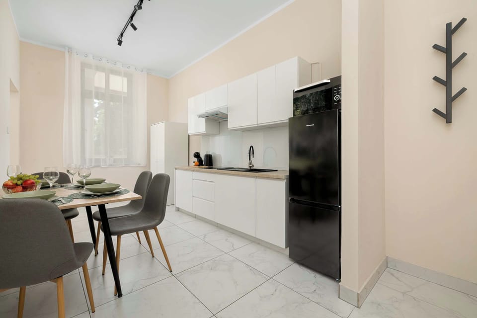 A view of the open-plan kitchen and dining area with a table for four guests. The bright interior creates a welcoming atmosphere.