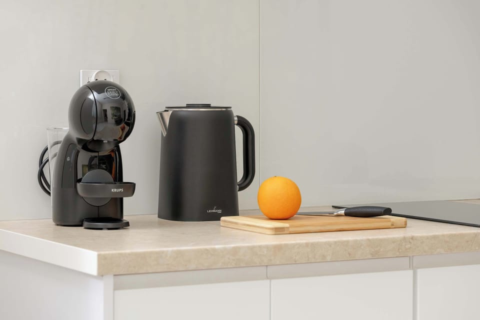 A close-up of the kitchen counter with a coffee machine, kettle, and workspace. The area is clean and well-equipped.