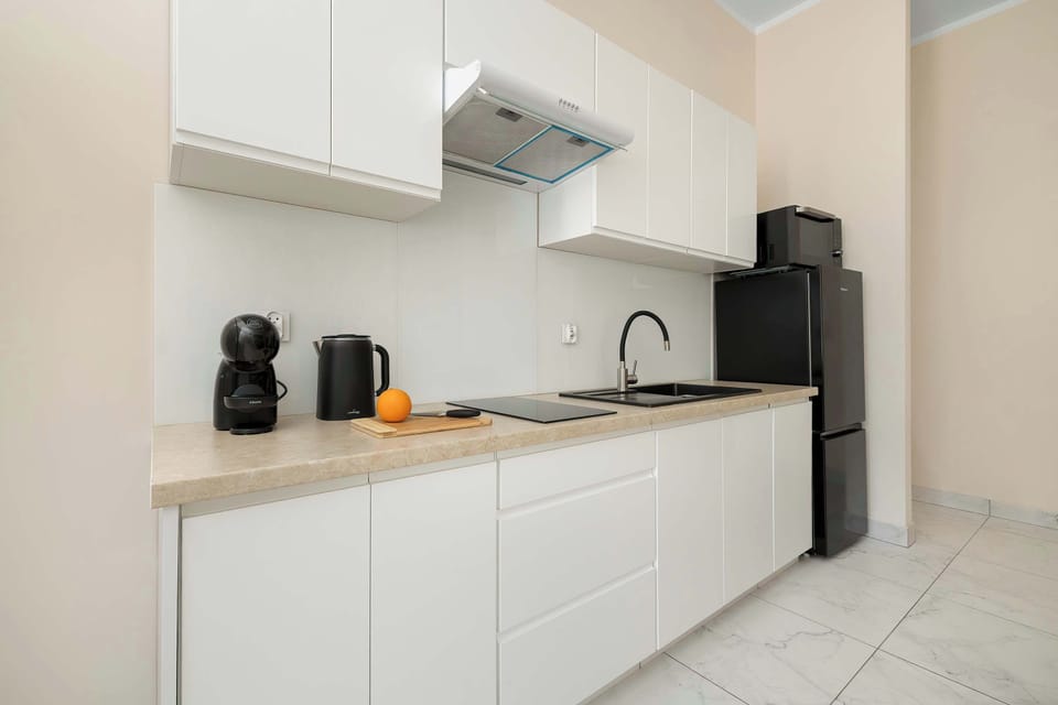 A modern kitchen with white cabinets and built-in appliances. The space is bright and functional.