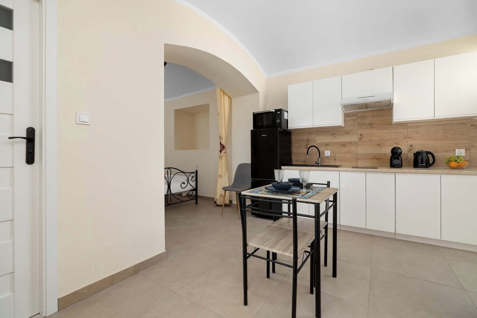 A hallway view leading toward the kitchen, with a small dining table visible in the background and a practical open-plan arrangement.