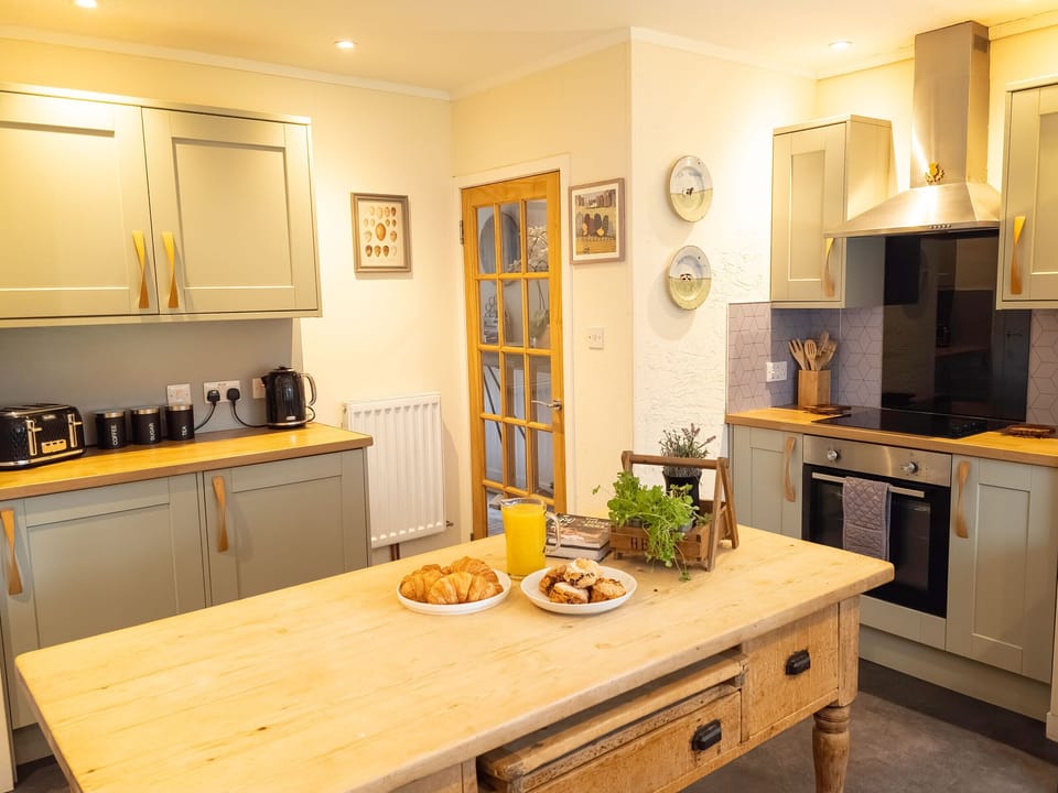 A big wooden table in the middle of the kitchen, with breakfast already out. Everything is within reach of whoever is cooking.