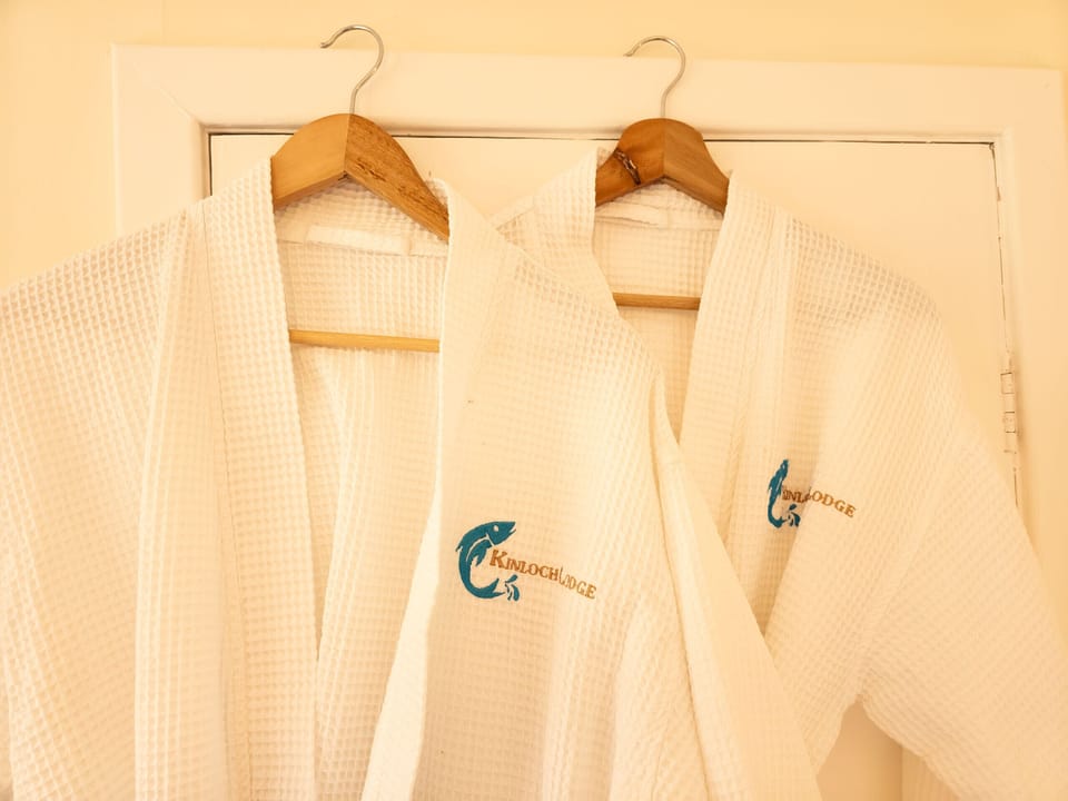 Two waffle robes hanging ready, each with the lodge's name stitched on. Handy for the short walk out to the hot tub.