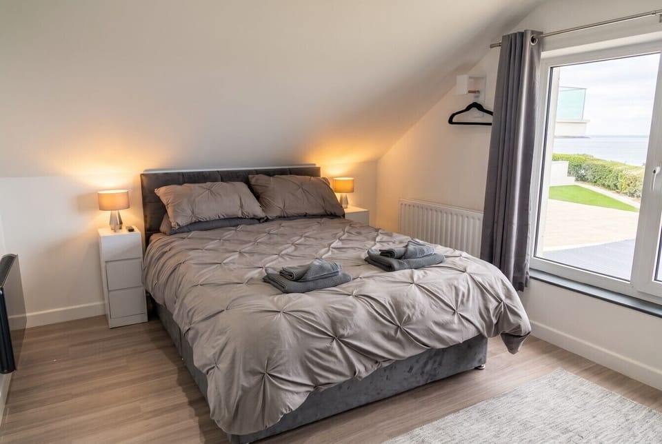 Restful bedroom with soft lighting, plush bedding and coastal views