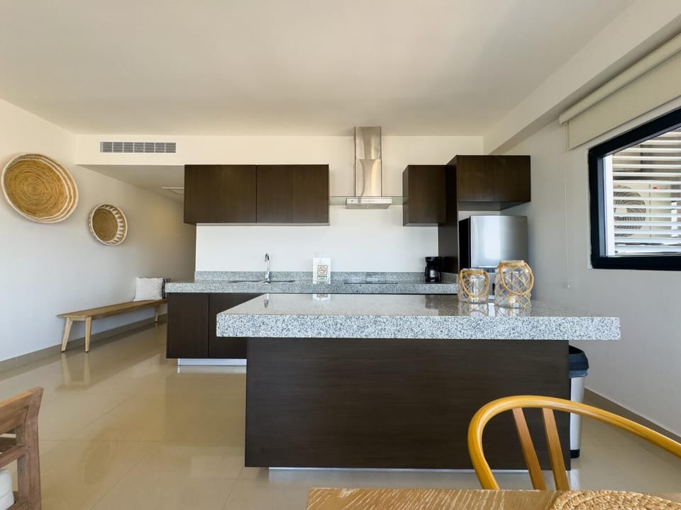 Kitchen with dark wood cabinetry, stainless steel range hood, granite countertops, and decorative woven baskets on white walls.