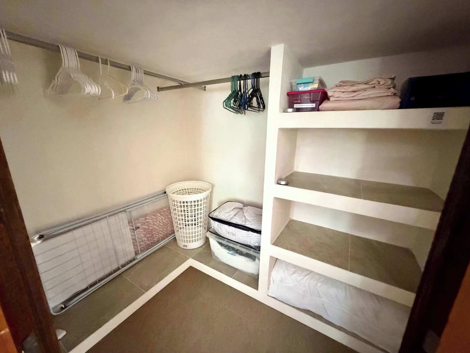 Large closet with iron, ironing board, laundry basket, valuables safe, first aid kit, extra linens, blanket, and pillows